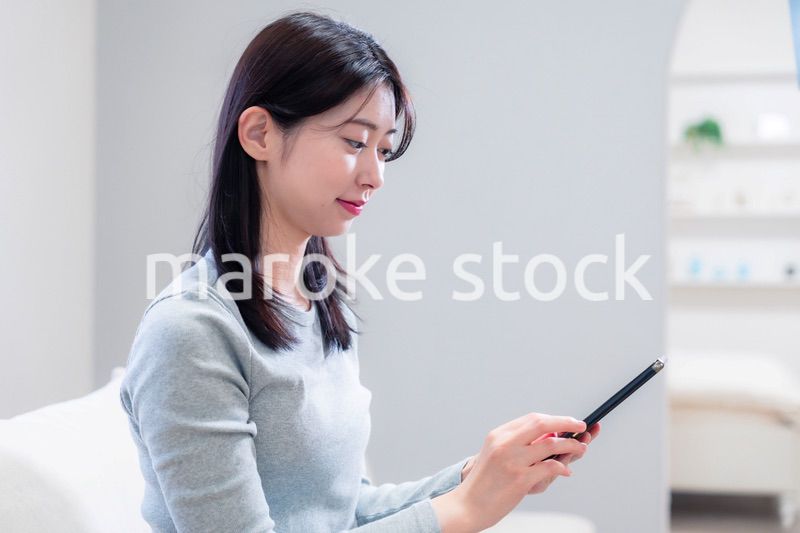 ソファでリラックスをしてスマホを使う若い女性