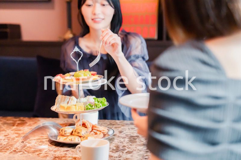 ホテルでアフタヌーンティーを楽しむ若い二人の女性