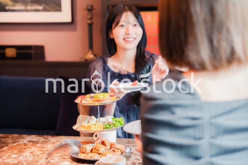 ホテルでアフタヌーンティーを楽しむ若い二人の女性