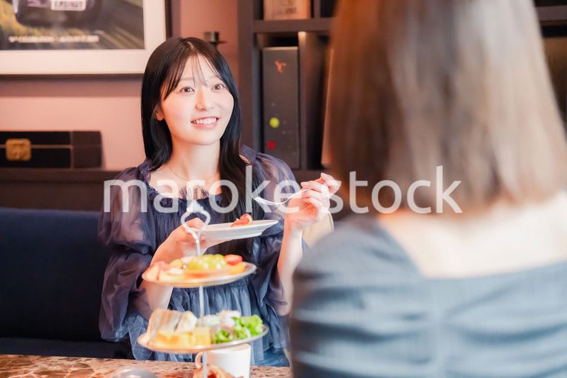 ホテルでアフタヌーンティーを楽しむ若い二人の女性