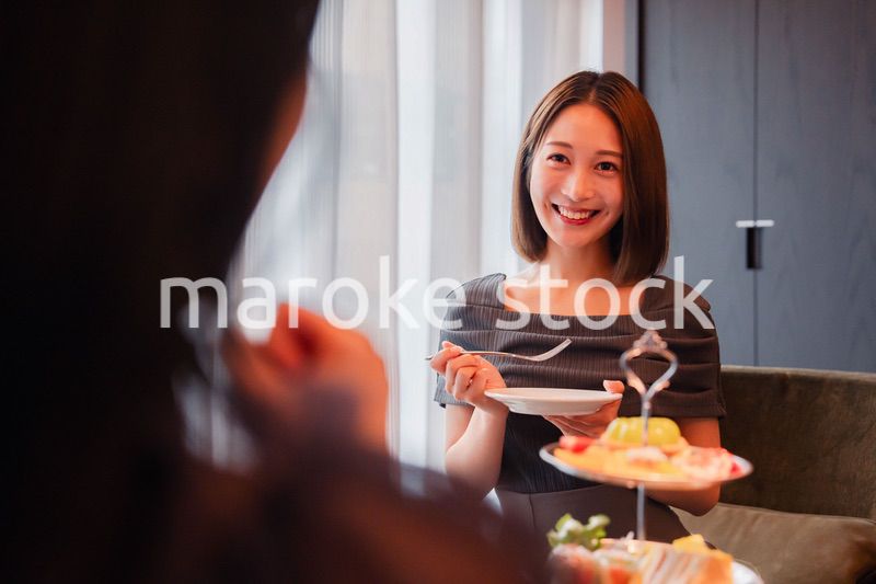 ホテルでアフタヌーンティーを楽しむ若い二人の女性