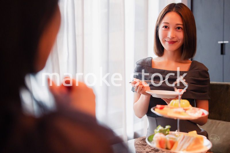 ホテルでアフタヌーンティーを楽しむ若い二人の女性