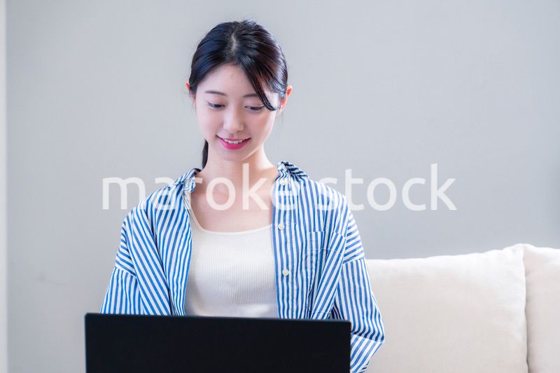 家で笑顔でパソコンを使う若い女性