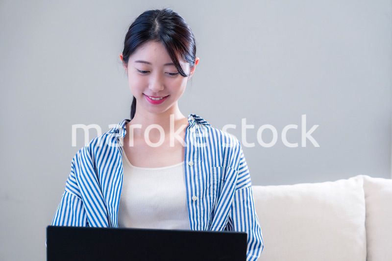 家で笑顔でパソコンを使う若い女性