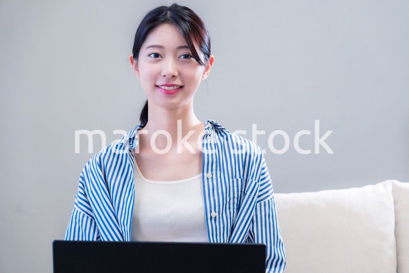 家で笑顔でパソコンを使う若い女性