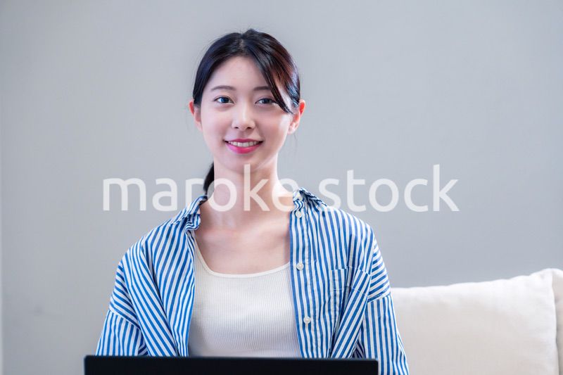 家で笑顔でパソコンを使う若い女性