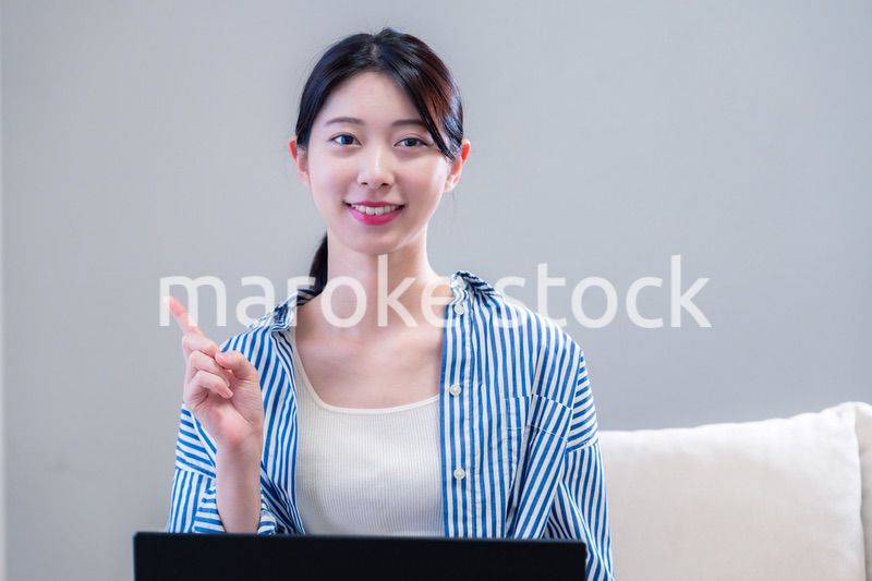 家で笑顔でパソコンを使う若い女性