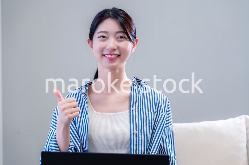 家で笑顔でパソコンを使う若い女性