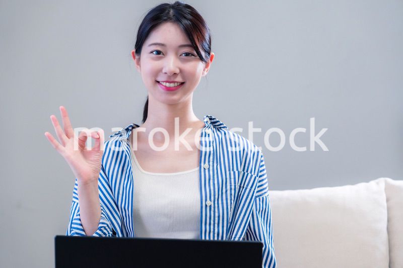 家で笑顔でパソコンを使う若い女性