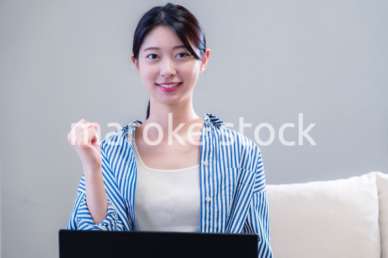 家で笑顔でパソコンを使う若い女性