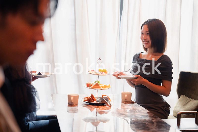 ホテルのアフタヌーンティーで女子会をする若い人々