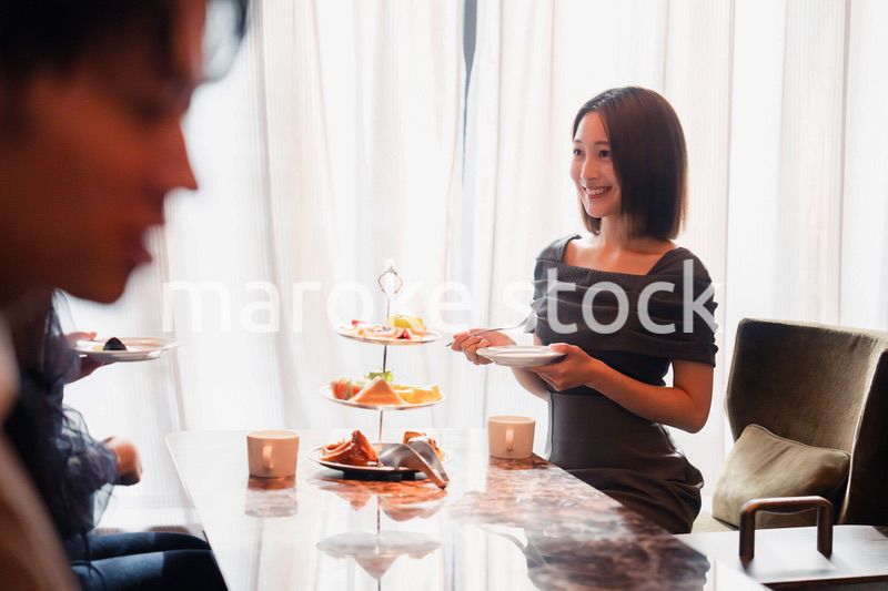 ホテルのアフタヌーンティーで女子会をする若い人々