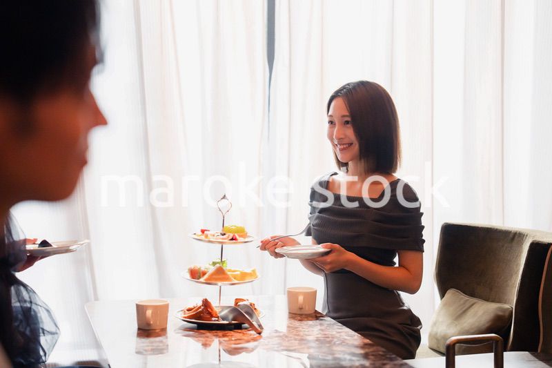 ホテルのアフタヌーンティーで女子会をする若い人々