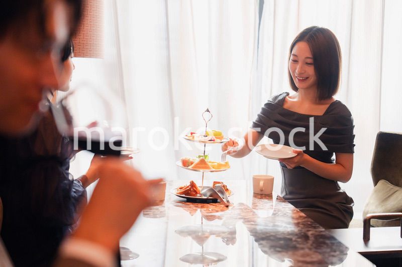 ホテルのアフタヌーンティーで女子会をする若い人々