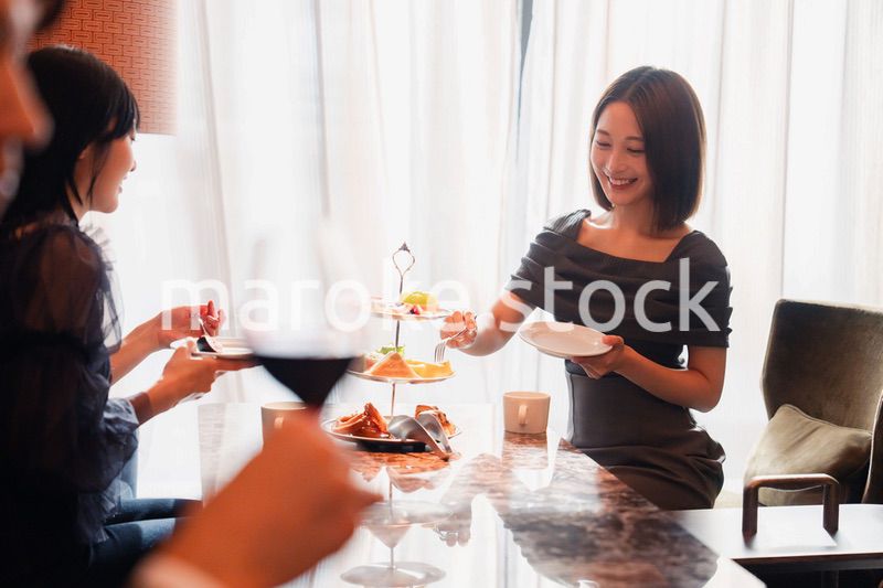 ホテルのアフタヌーンティーで女子会をする若い人々