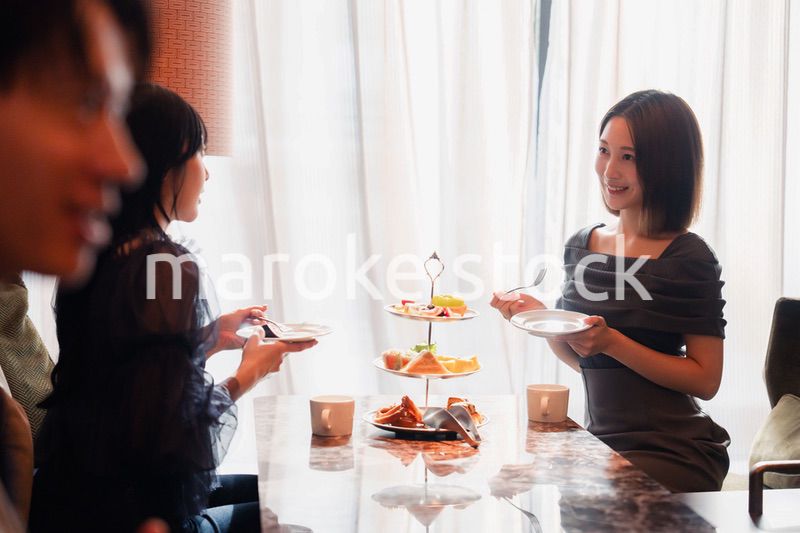 ホテルのアフタヌーンティーで女子会をする若い人々