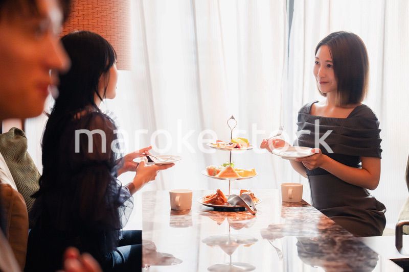 ホテルのアフタヌーンティーで女子会をする若い人々