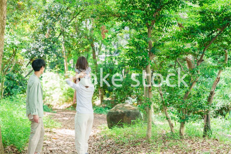 子どもを肩車して森の中を歩く家族