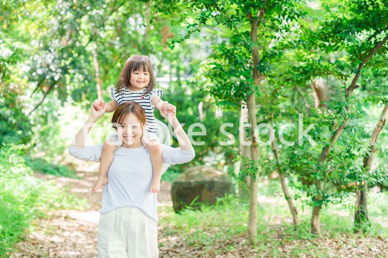 子どもを肩車して森の中を歩く家族