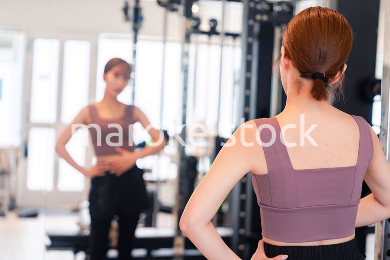 ジムで自分の体型を確認する若い女性