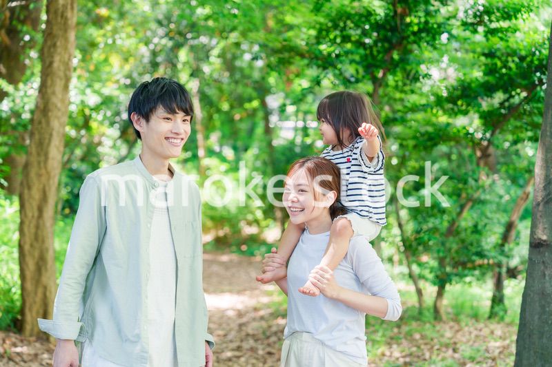 子どもを肩車して森の中を歩く家族
