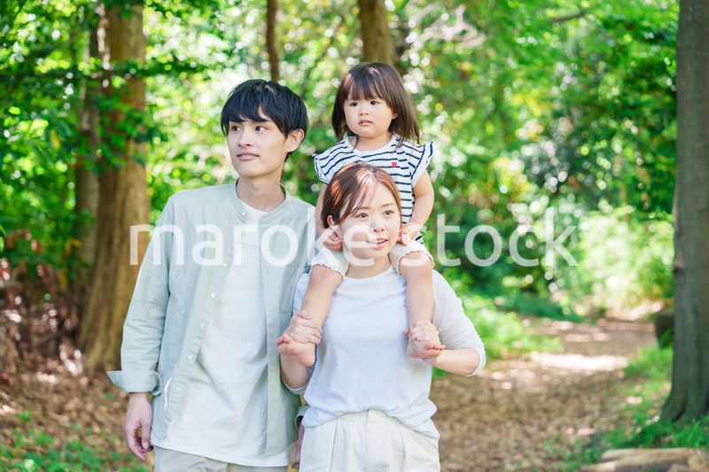 子どもを肩車して森の中を歩く家族