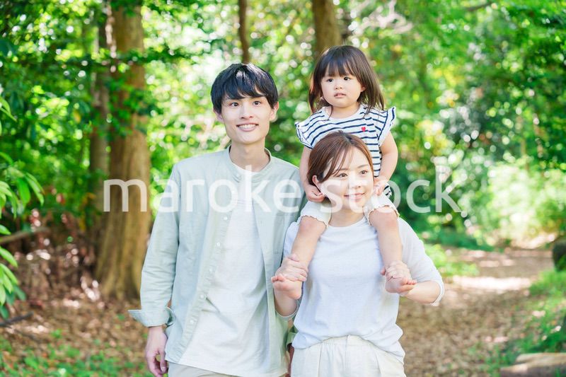 子どもを肩車して森の中を歩く家族