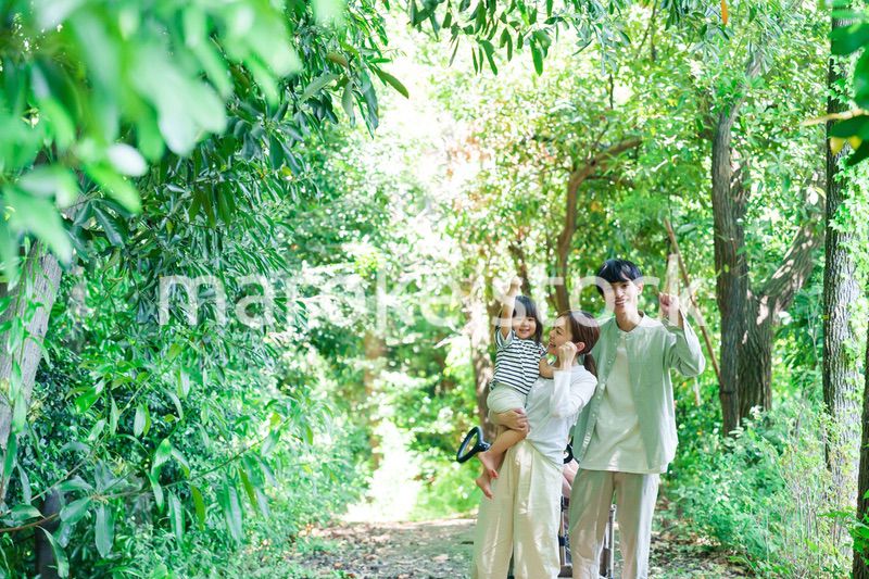 自然の中を歩いてアウトドアを楽しむ若いファミリー