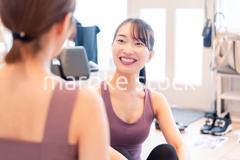 女性トレーナーからの指導を受けて筋トレをする女性