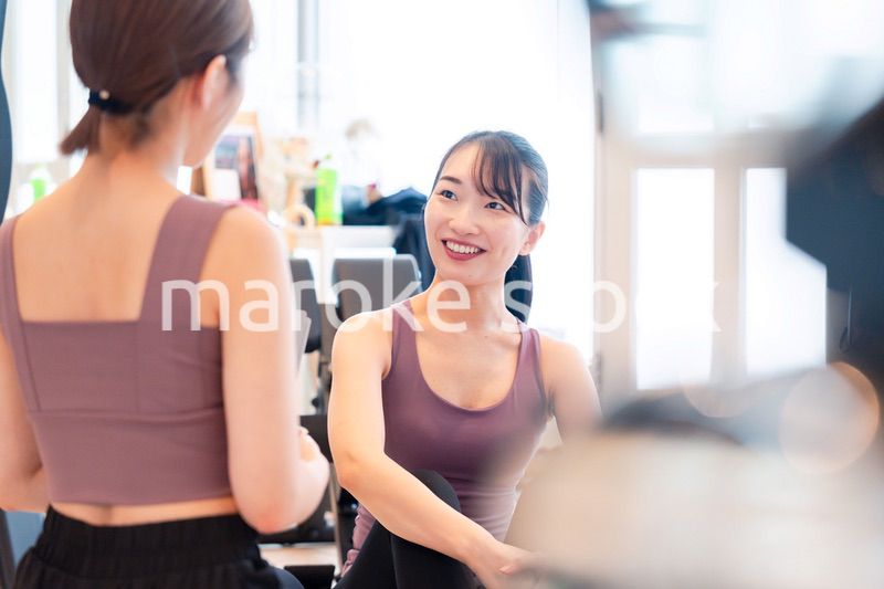 女性トレーナーからの指導を受けて筋トレをする女性