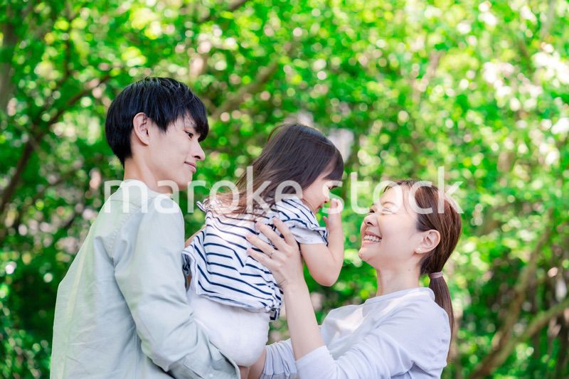 緑の中で子供を抱っこする家族