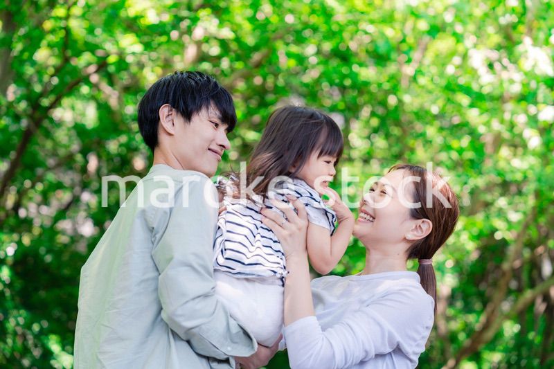 緑の中で子供を抱っこする家族