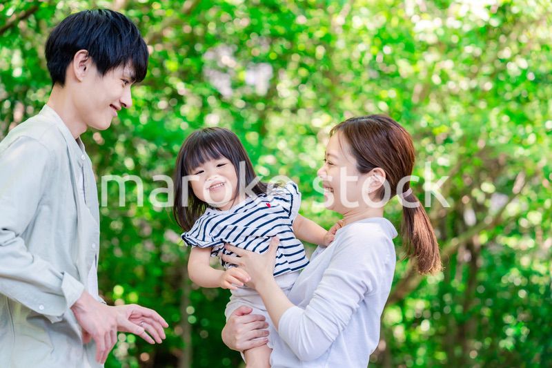 緑の中で子供を抱っこする家族