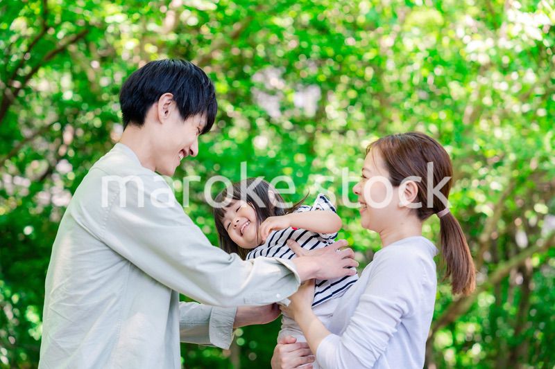 緑の中で子供を抱っこする家族