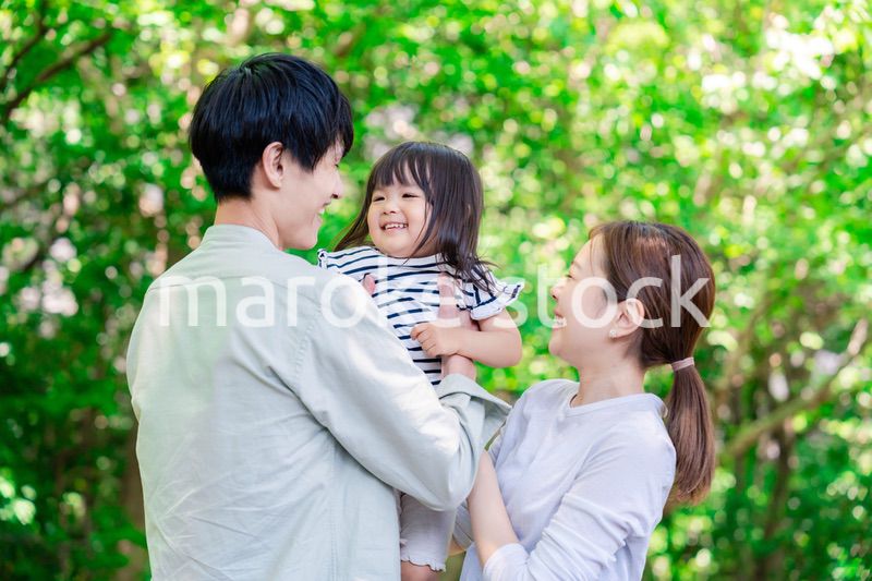 緑の中で子供を抱っこする家族