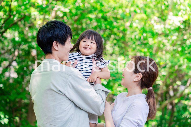 緑の中で子供を抱っこする家族