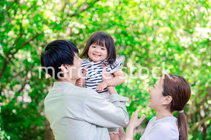緑の中で子供を抱っこする家族