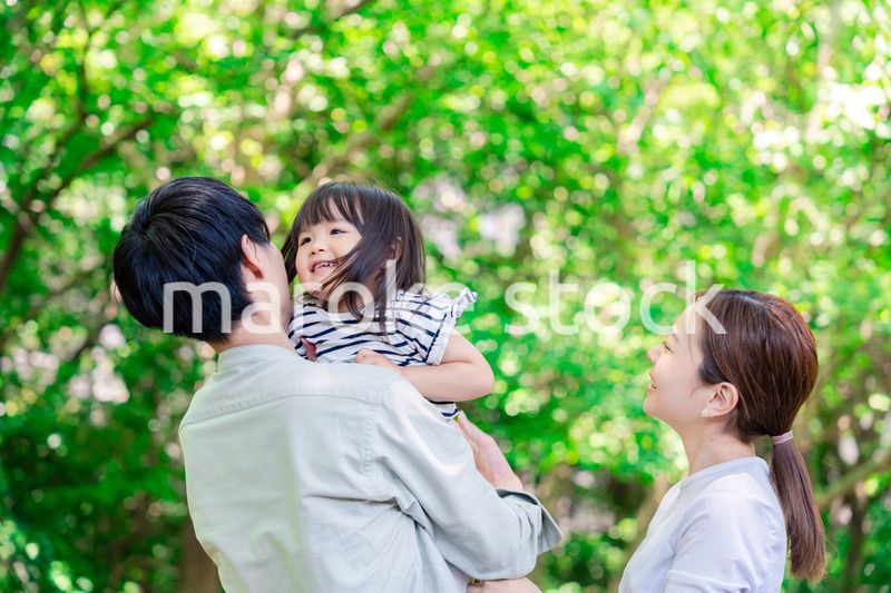 緑の中で子供を抱っこする家族