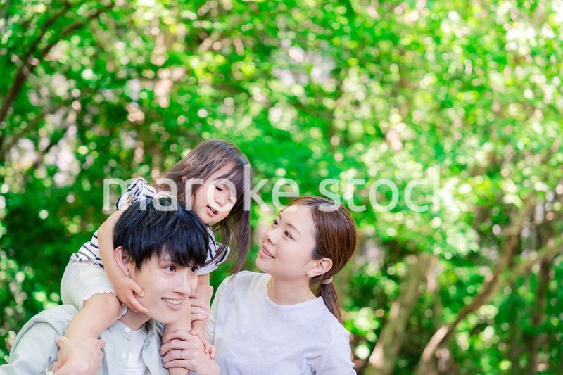 緑の中で子供を抱っこする家族