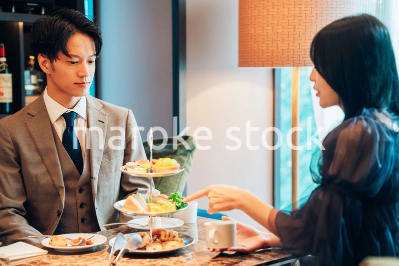 若い女性とアフタヌーンティーを楽しむ男性
