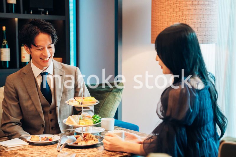 若い女性とアフタヌーンティーを楽しむ男性