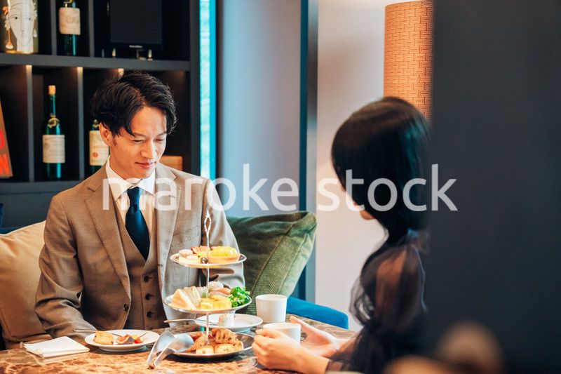 若い女性とアフタヌーンティーを楽しむ男性