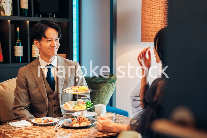 若い女性とアフタヌーンティーを楽しむ男性