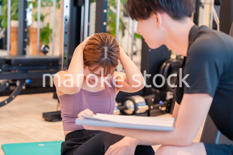 パーソナルジムに通う女性とトレーナー