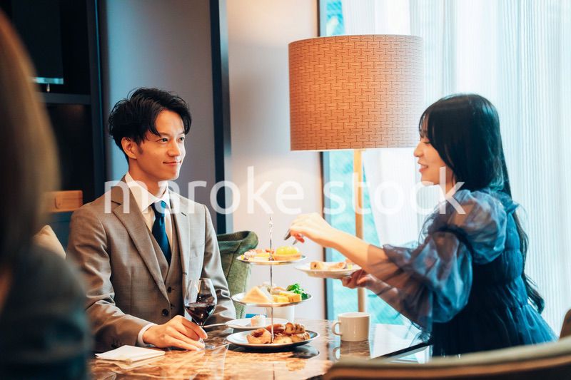 若い女性とアフタヌーンティーを楽しむ男性