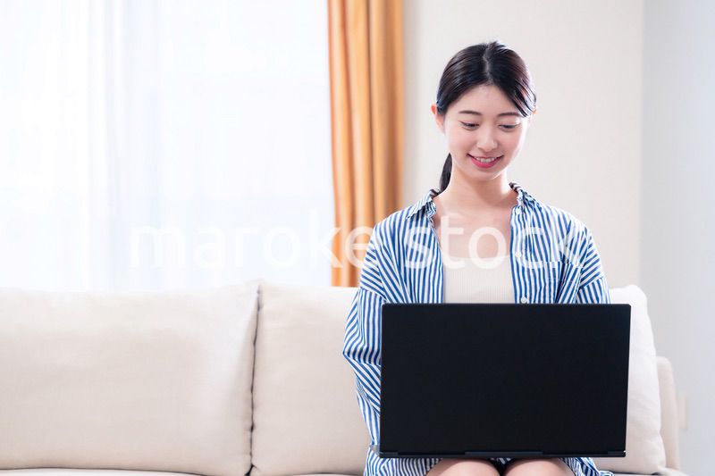 家でリラックスをしてパソコンを使う若い女性