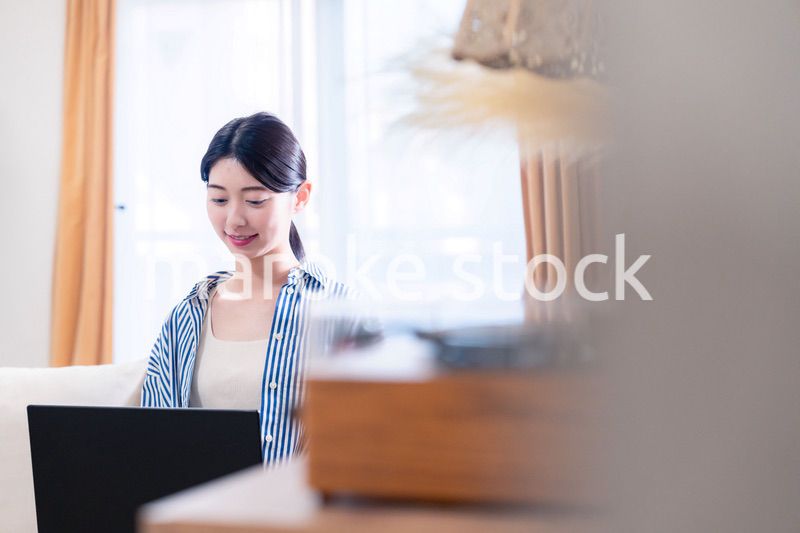 家でリラックスをしてパソコンを使う若い女性