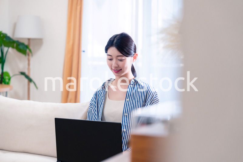 家でリラックスをしてパソコンを使う若い女性