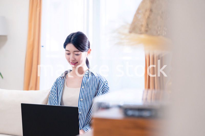 家でリラックスをしてパソコンを使う若い女性