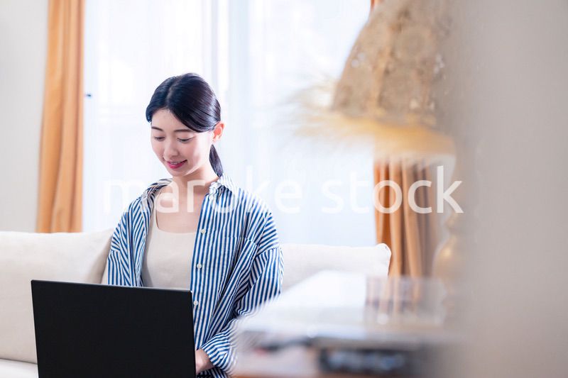 家でリラックスをしてパソコンを使う若い女性